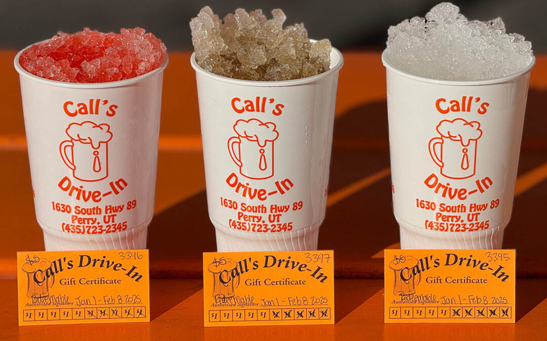 Image of vintage drink cups at Call's with gift cards in front of them on the picnic tables at Drive-In